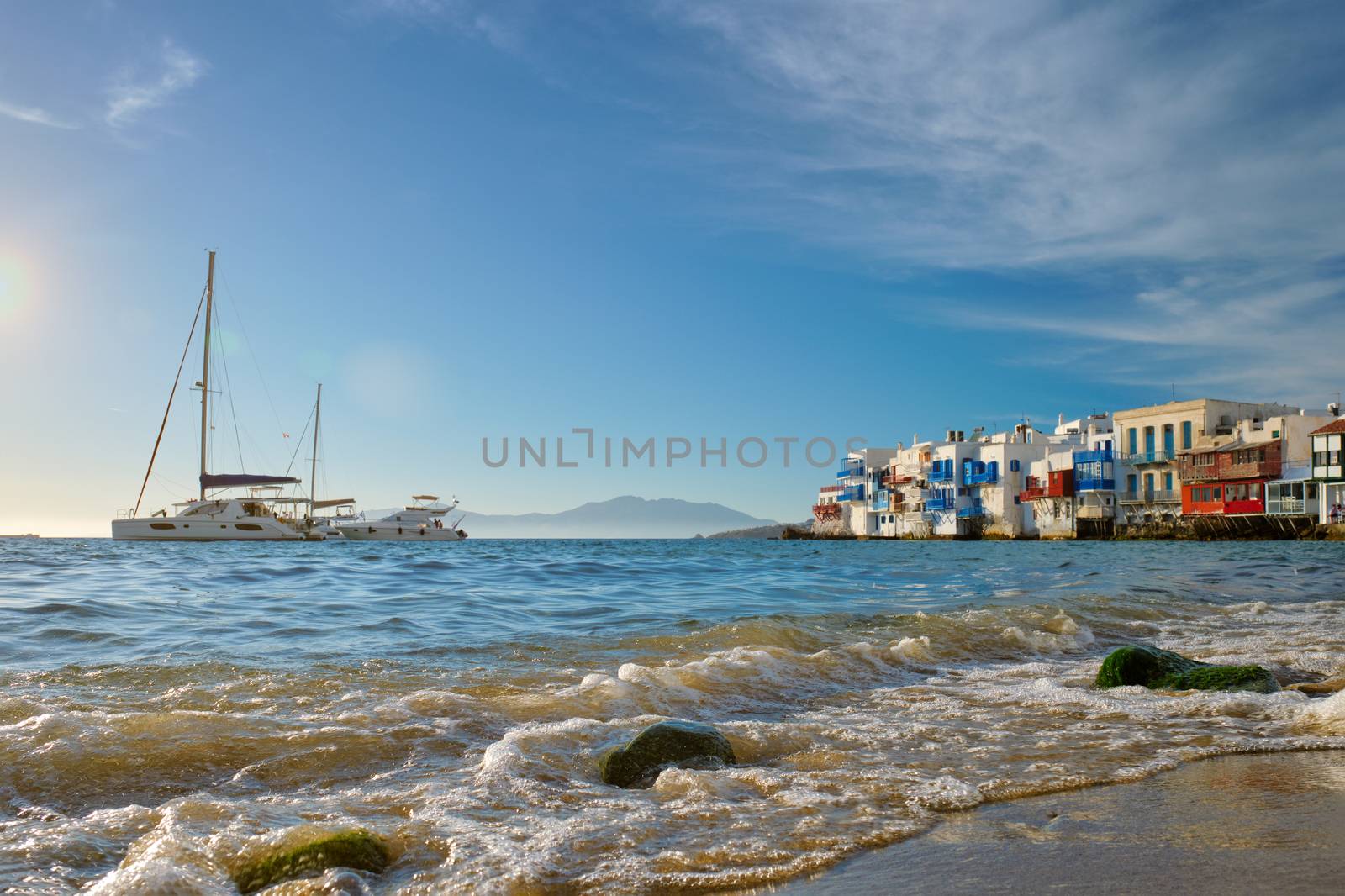 Sunset in Mykonos island, Greece with yachts in the harbor and colorful waterfront houses of Little Venice romantic spot on sunset and cruise ship. Mykonos townd, Greece