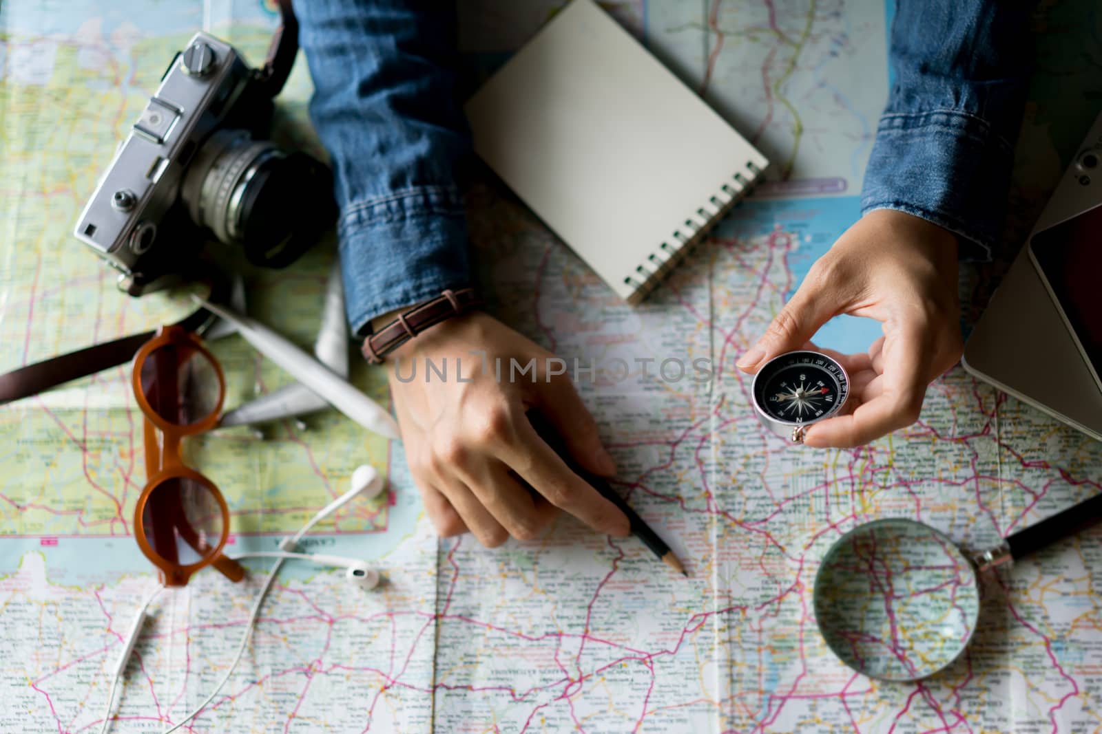 Hand holding compass for planning vacation trip and accessories for travel