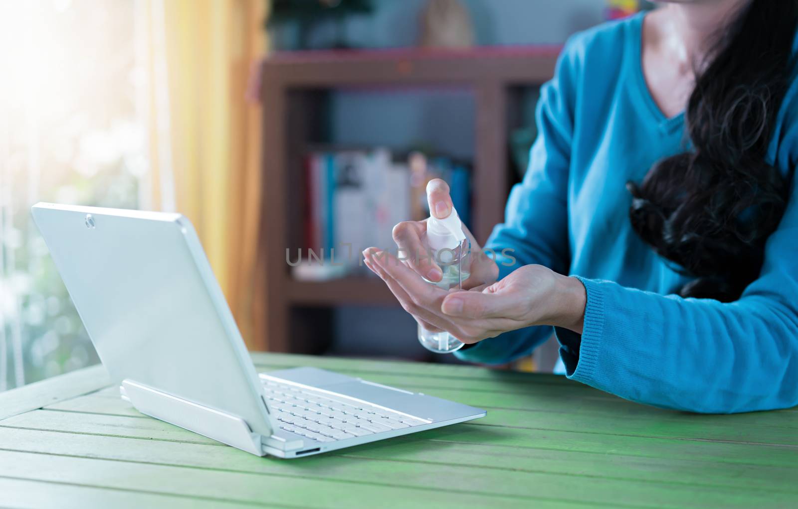 Woman working from home. Cleaning her hands with sanitizer gel.