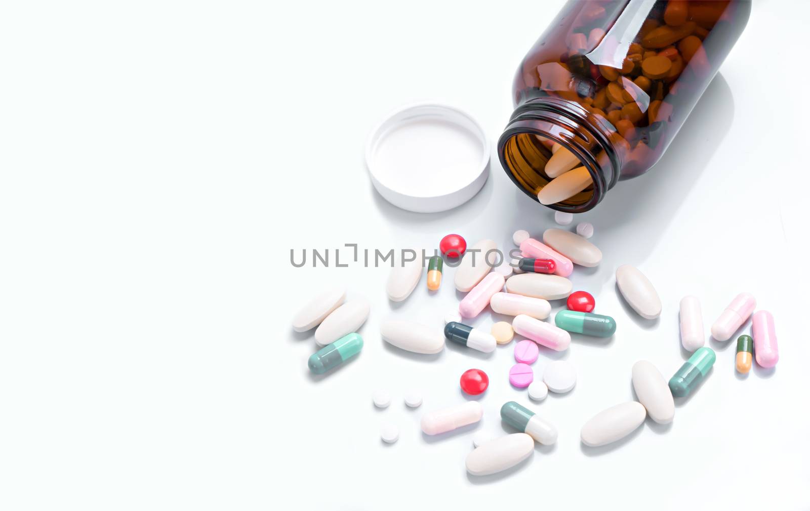 Pills spilling out of bottle on isolated white background by Buttus_casso
