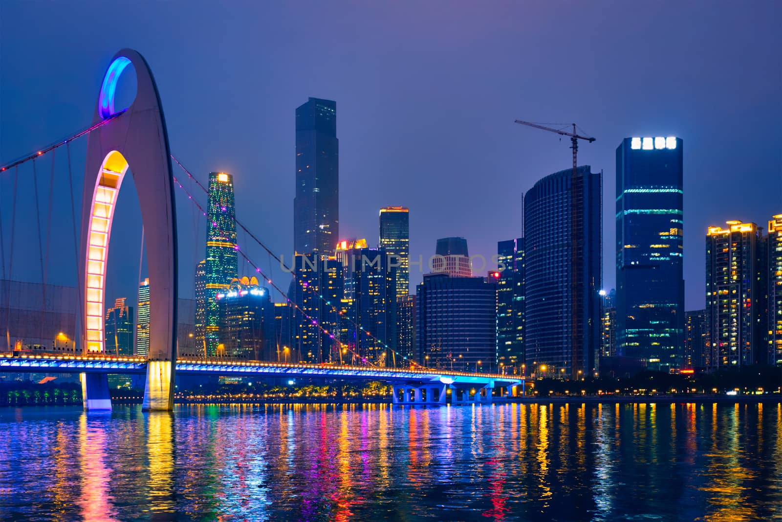 Guangzhou cityscape skyline over the Pearl River with Liede Bridge illuminated in the evening. Guangzhou, China