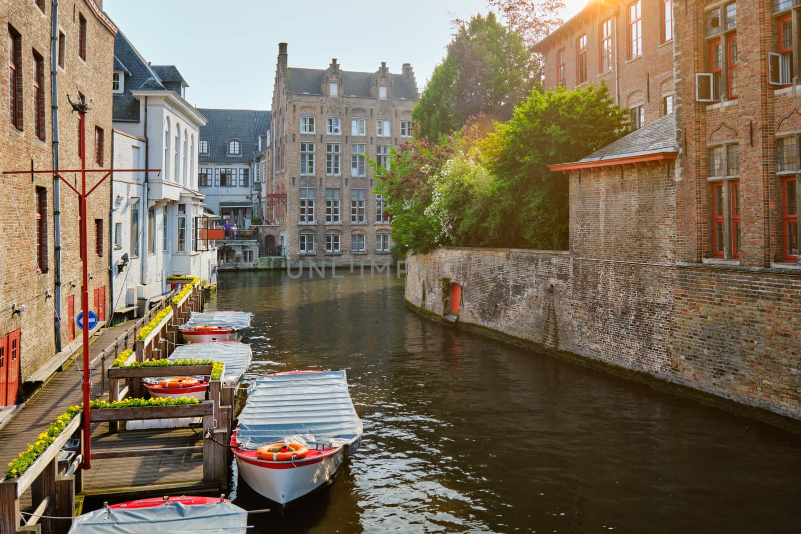 Famous place of Bruges - Rozenhoedkaai old houses along canal with tree and boats. Brugge, Belgium