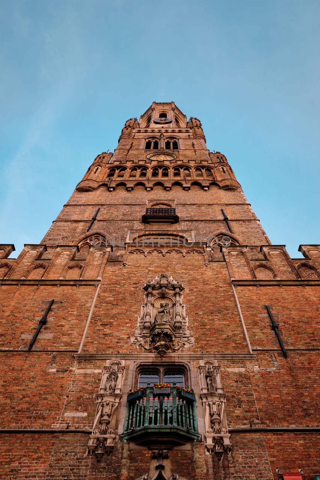 Brugge Belfry tower facade details at Grote markt square in Bruges, Belgium on sunset by dimol