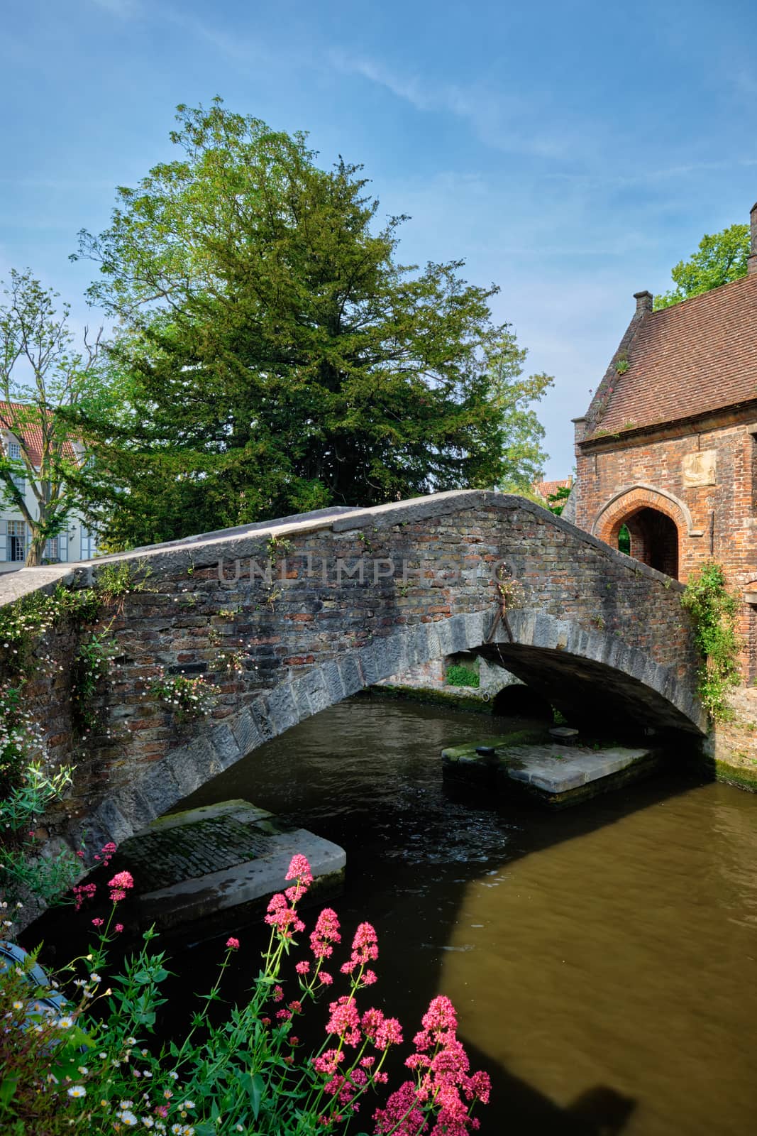 Famous tourist tourism spot for selfile old Bonifacius Bridge over Brugge canal and medieval houses with flowers in Bruges, Belgium