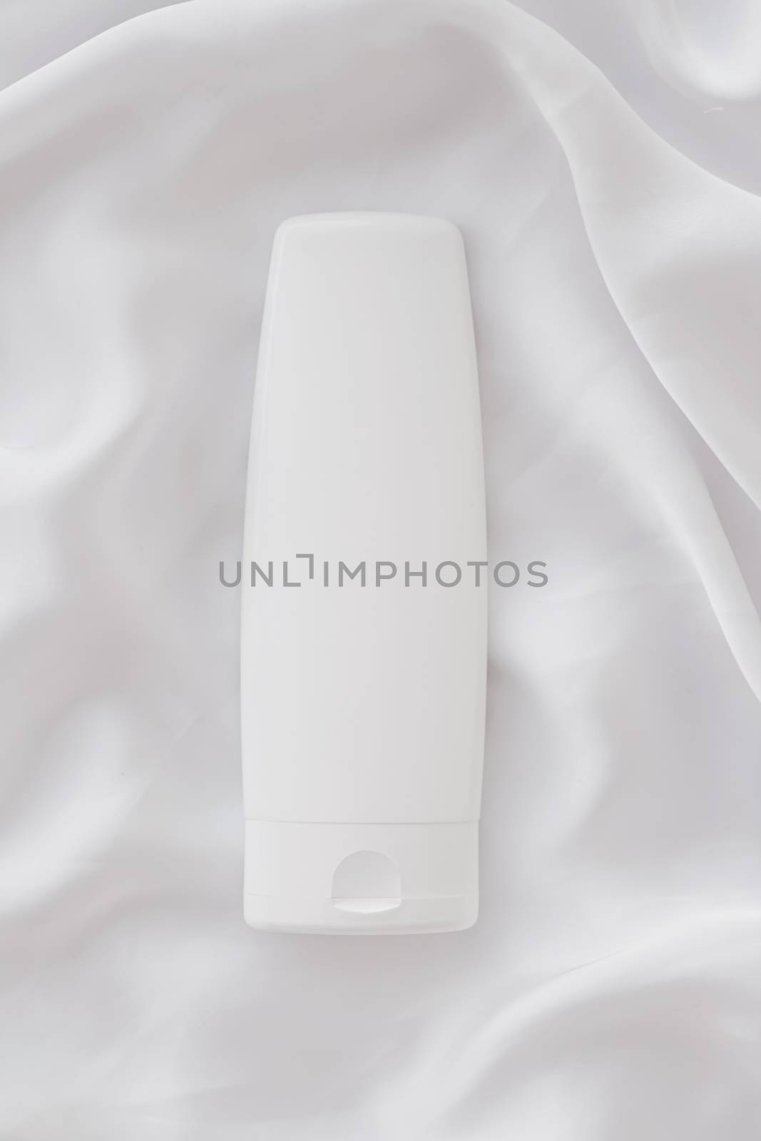 Blank label cosmetic container bottle as product mockup on white silk background by Anneleven