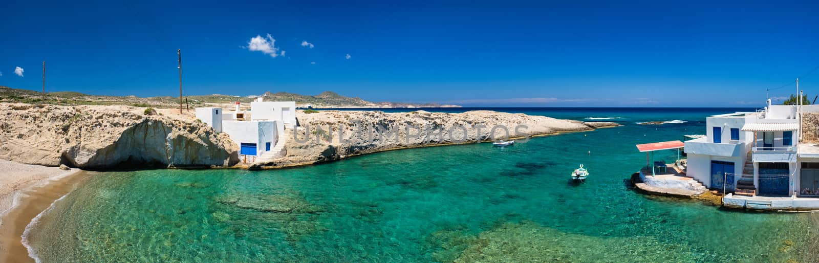 Greece scenic island panorama - small harbor with fishing boats in crystal clear turquoise water, traditishional whitewashed house. MItakas village, Milos island, Greece.