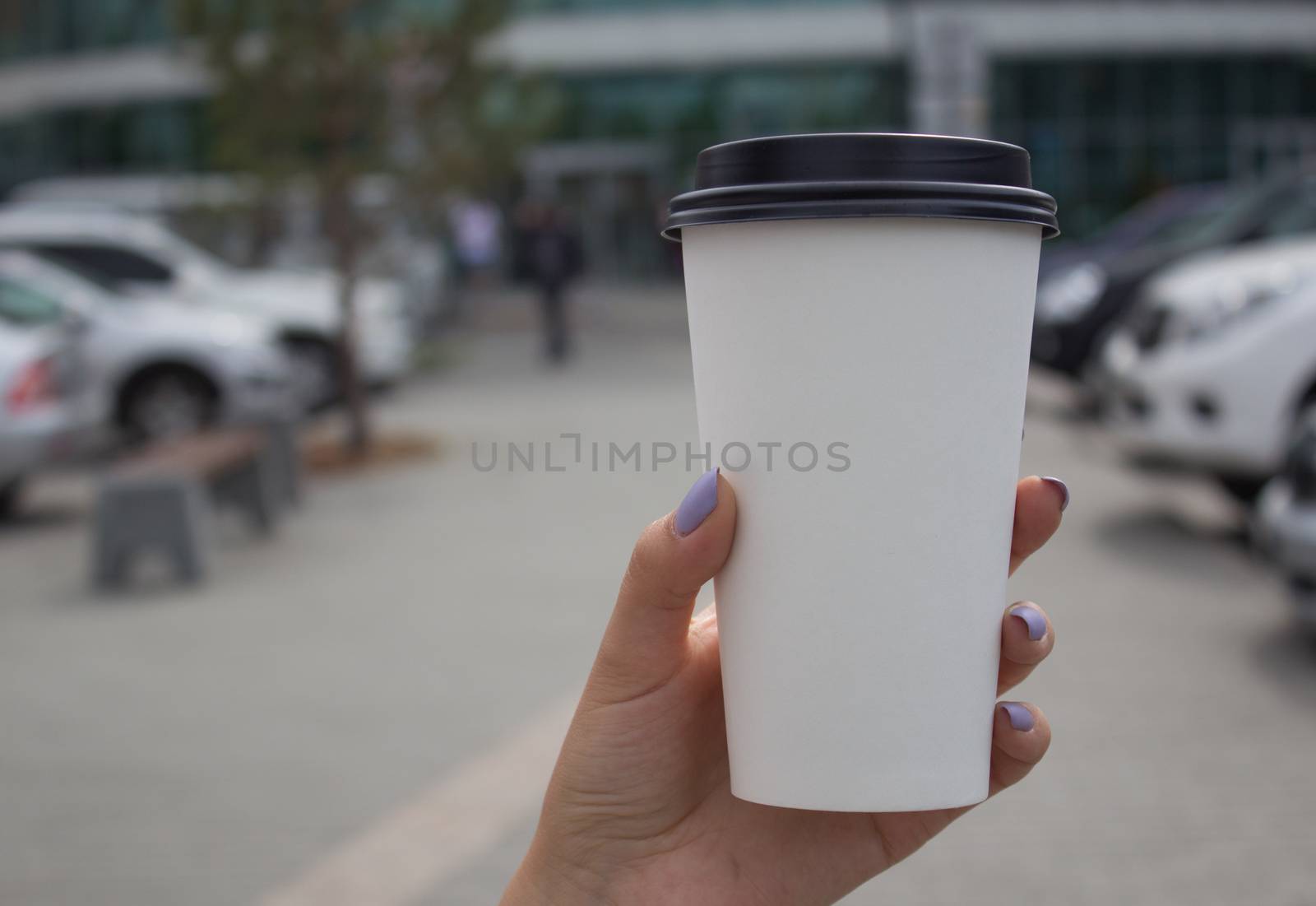 Breakfast and coffee theme: a woman's hand holding a white paper coffee Cup with a black plastic lid. by AnatoliiFoto