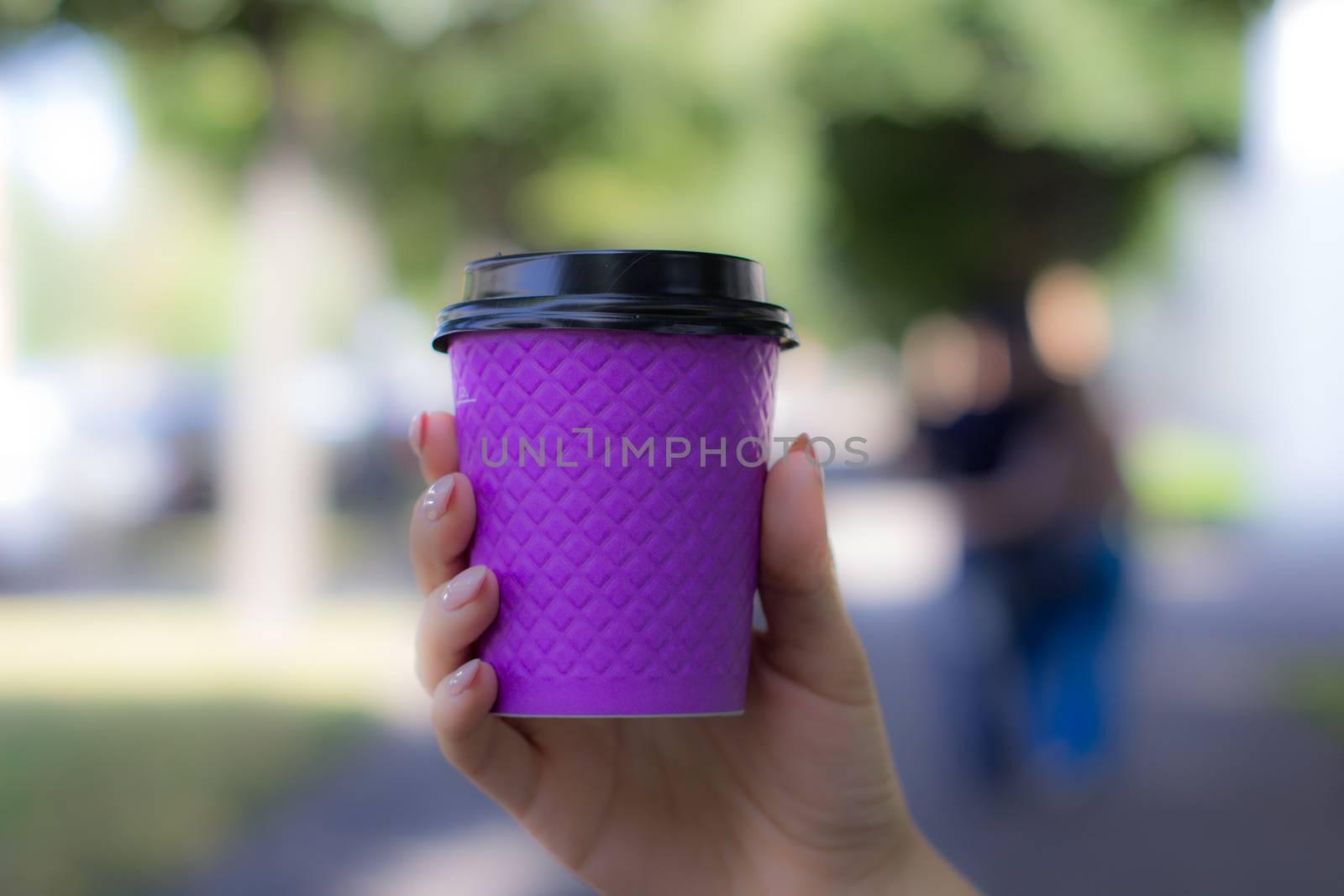 Purple cardboard Cup for coffee in a woman's hand