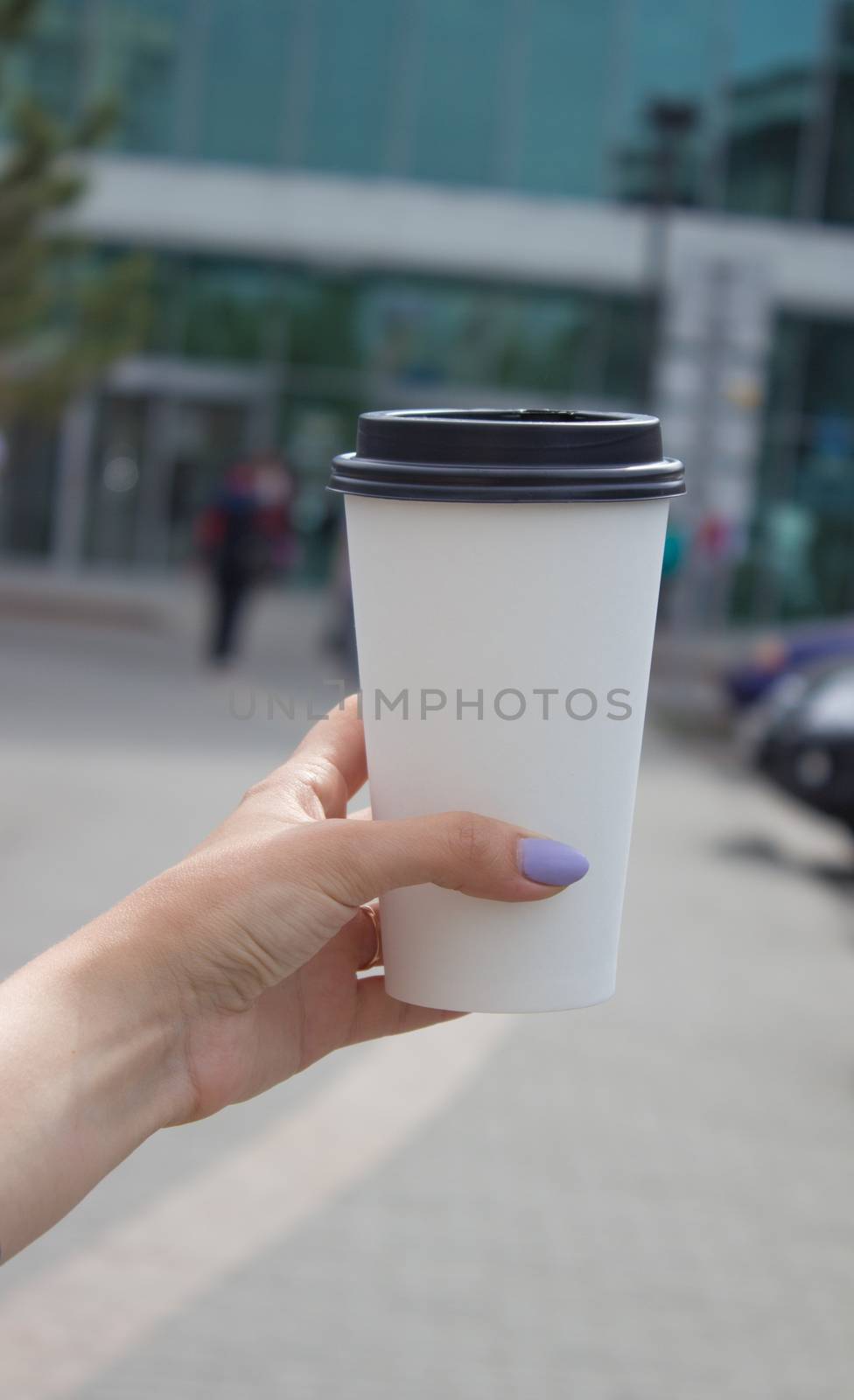 Breakfast and coffee theme: a woman's hand holding a white paper coffee Cup with a black plastic lid. by AnatoliiFoto