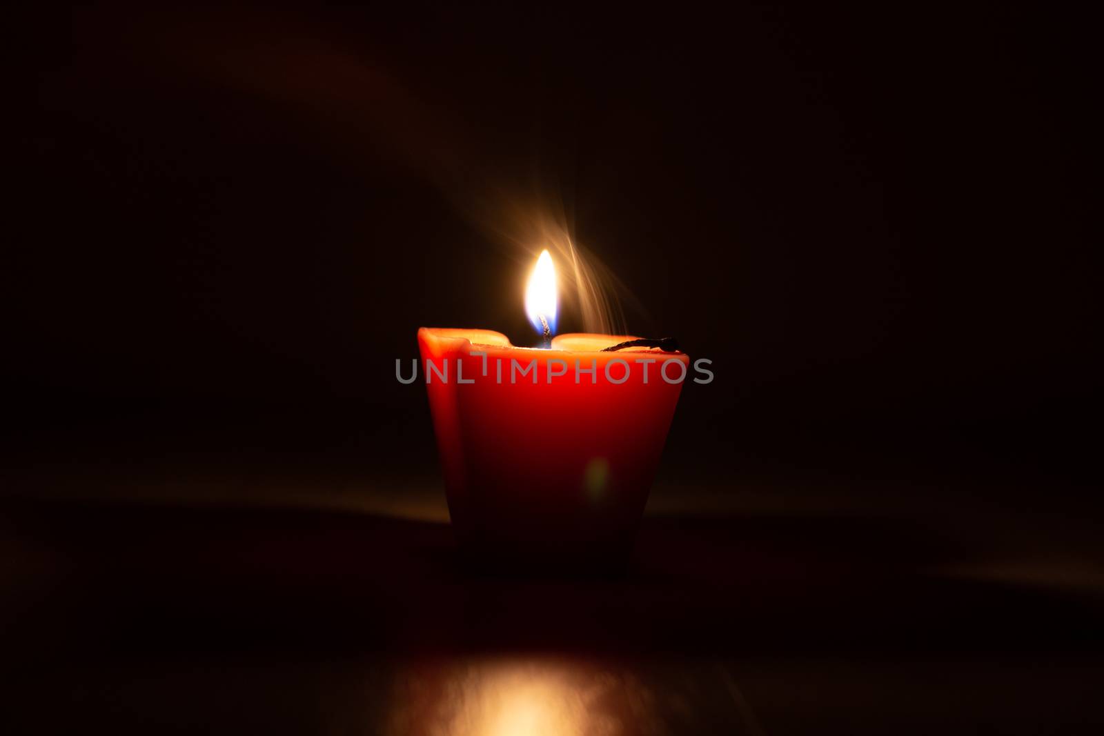 Yellow candle with smoke trailing off the wick in the dark. Candle out of fire and light then white smoke happen. by AnatoliiFoto