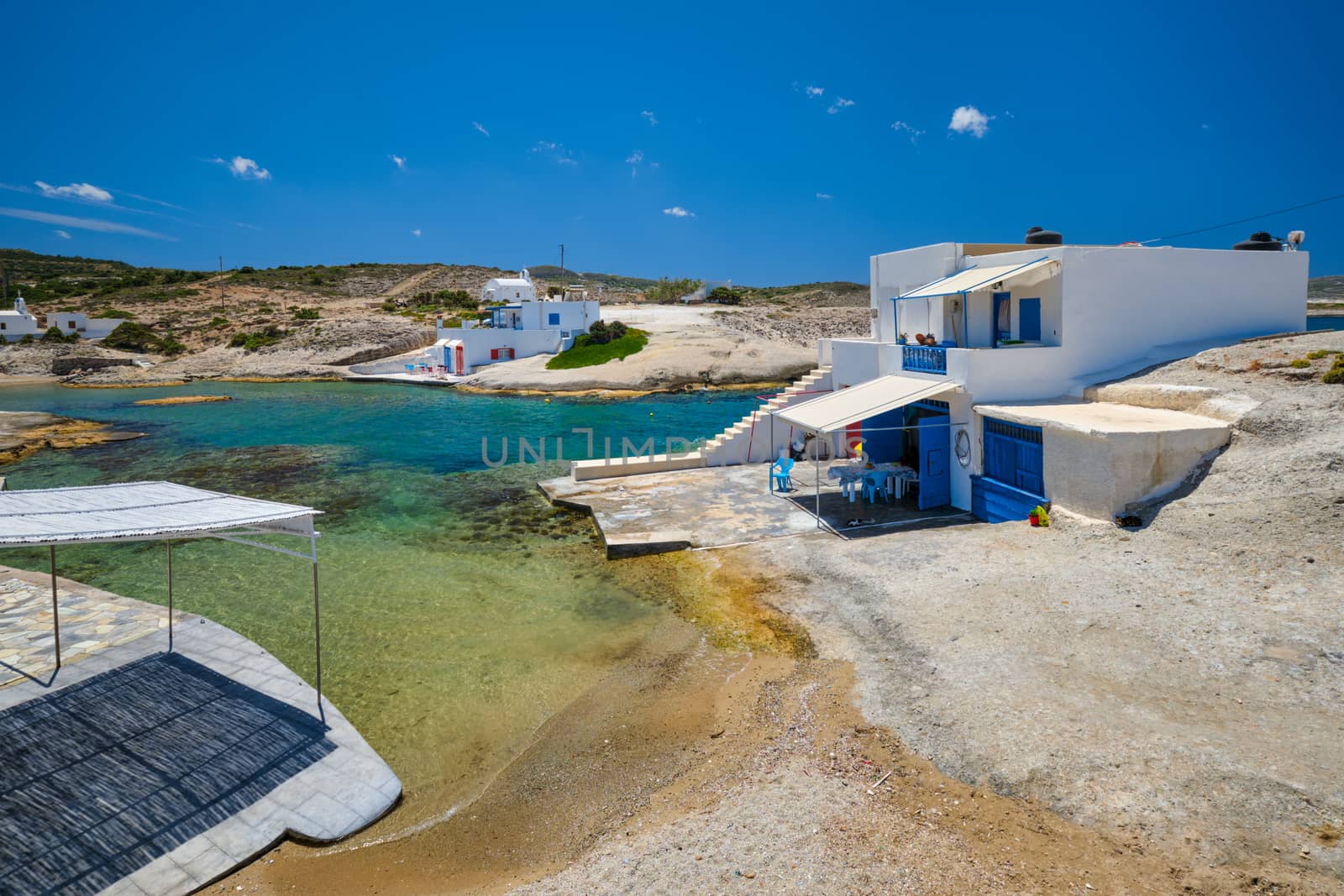 Greece scenic island view - small harbor with crystal clear turquoise water, traditishional whitewashed house. Pachena village, Milos island, Greece.