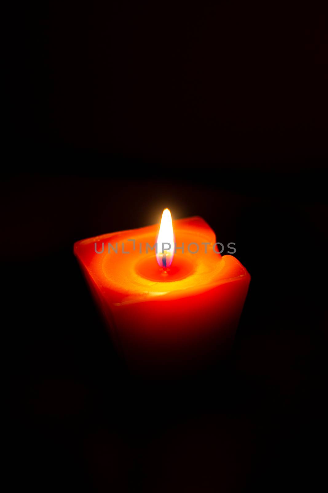 Closeup of burning candle isolated on black background.