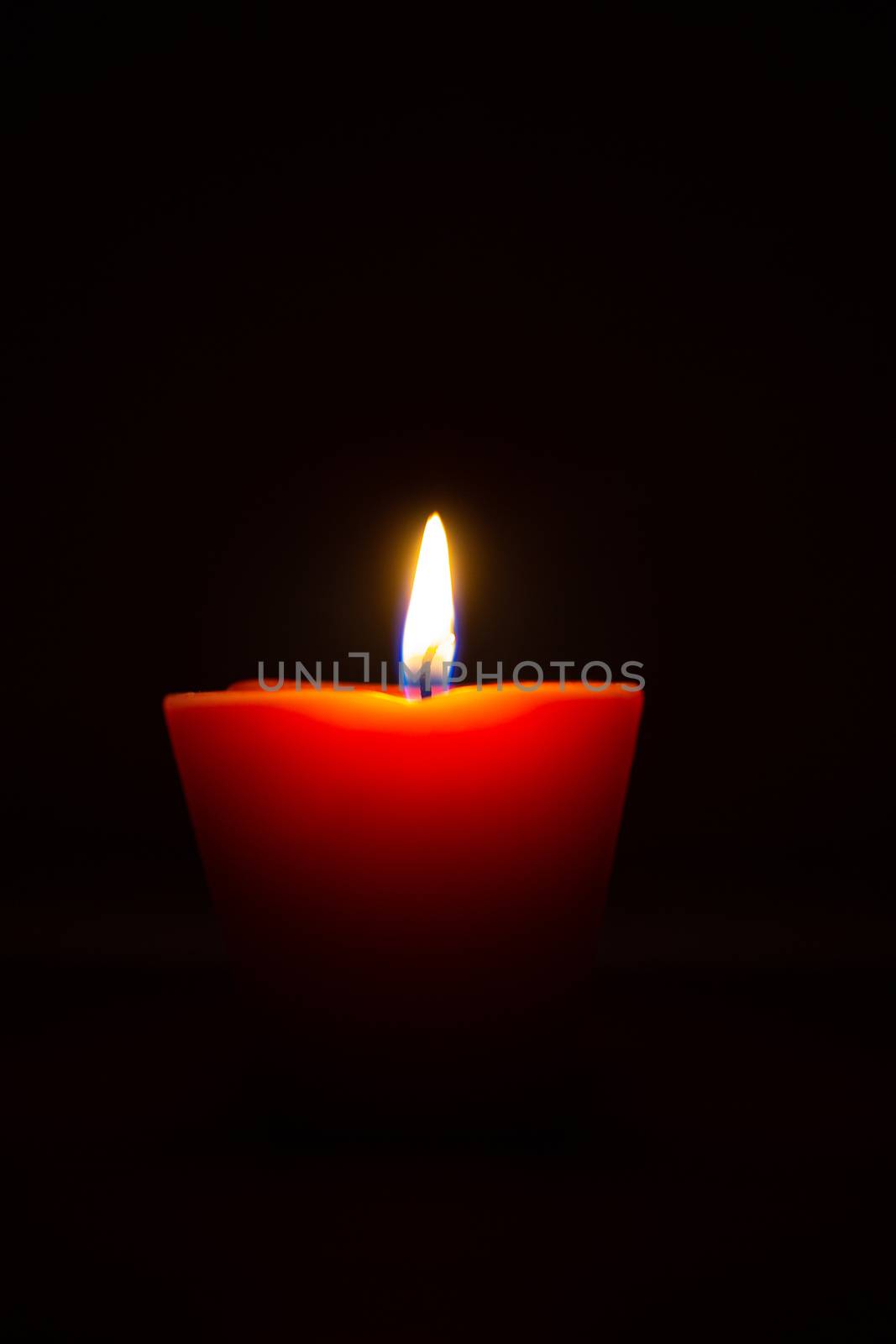 Closeup of burning candle isolated on black background.