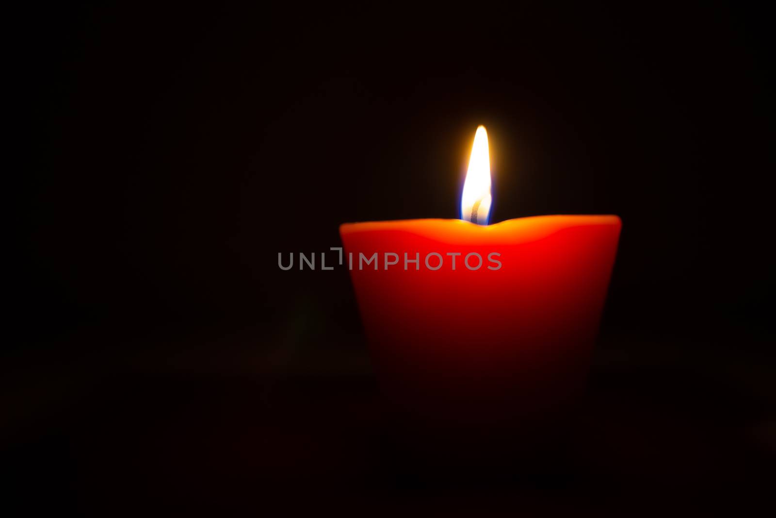 Closeup of burning candle isolated on black background.