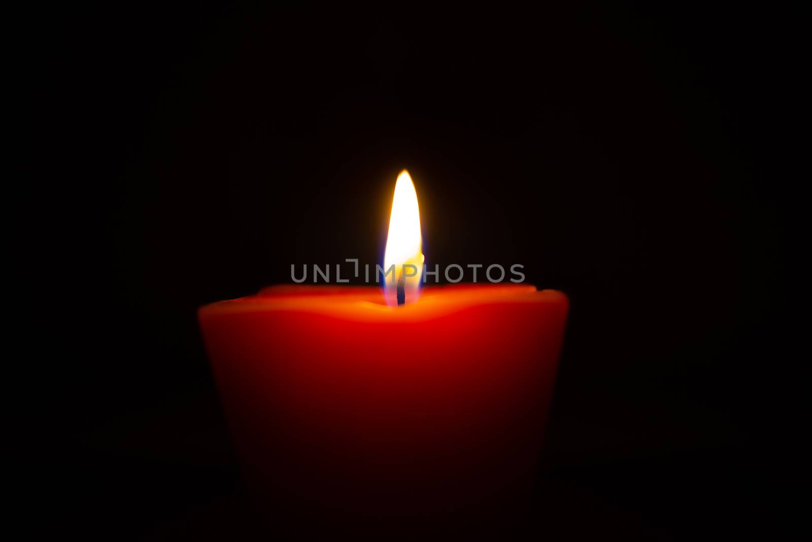 Closeup of burning candle isolated on black background.