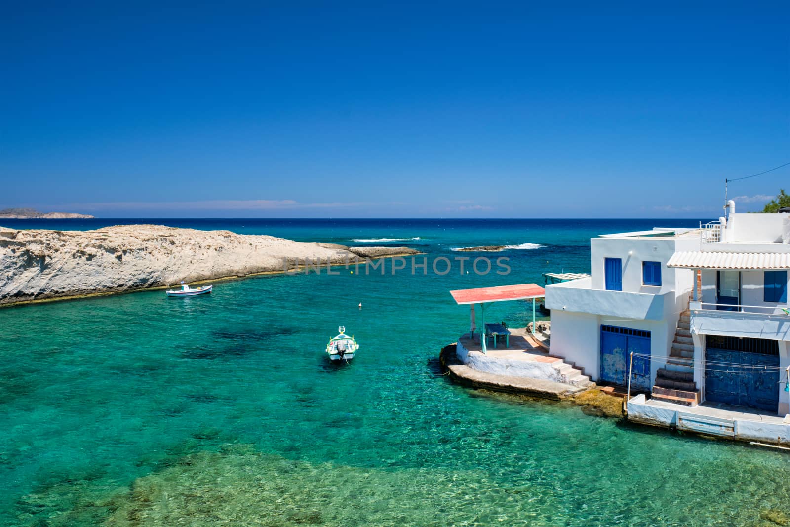 Greece island Milos. Small harbor with fishing boats in water, whitewashed house. Mitakas village by dimol