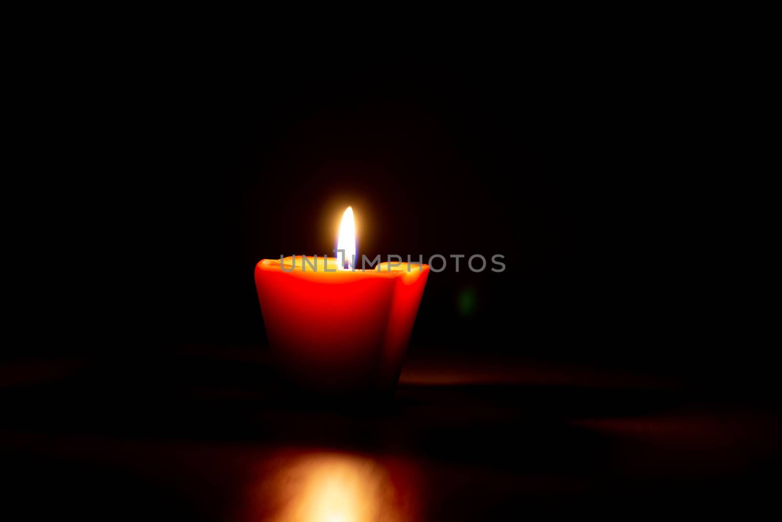 Closeup of burning candle isolated on black background.