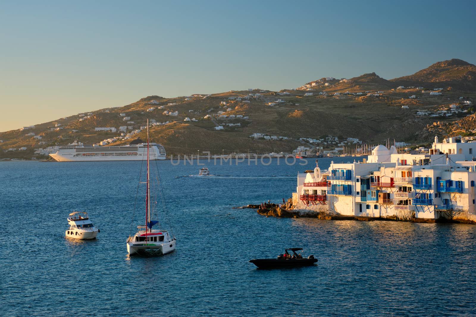 Sunset in Mykonos, Greece, with cruise ship and yachts in the harbor by dimol