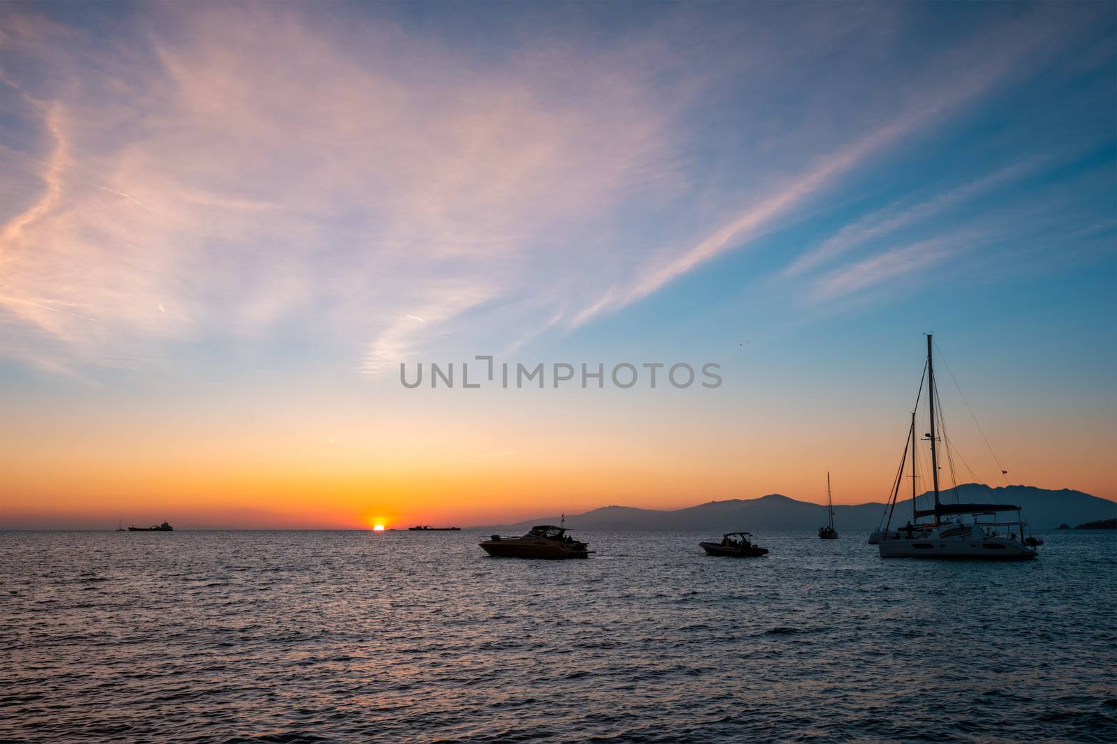 Sunset in Mykonos, Greece and yachts in the harbor by dimol