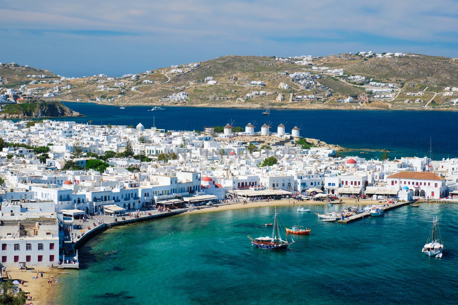 View of Mykonos town Greek tourist holiday vacation destination with famous windmills, and port with boats and yachts. Mykonos, Cyclades islands, Greece