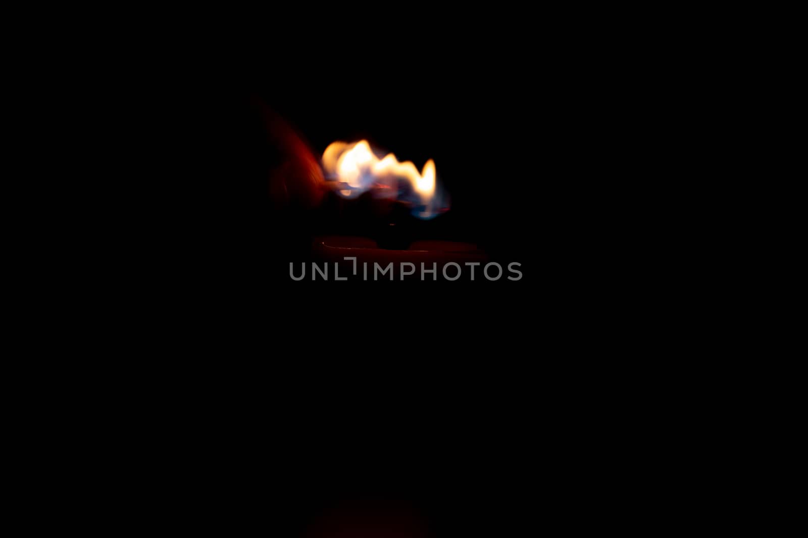 Hand with a match ignites a candle in the dark. Memorable event. by AnatoliiFoto