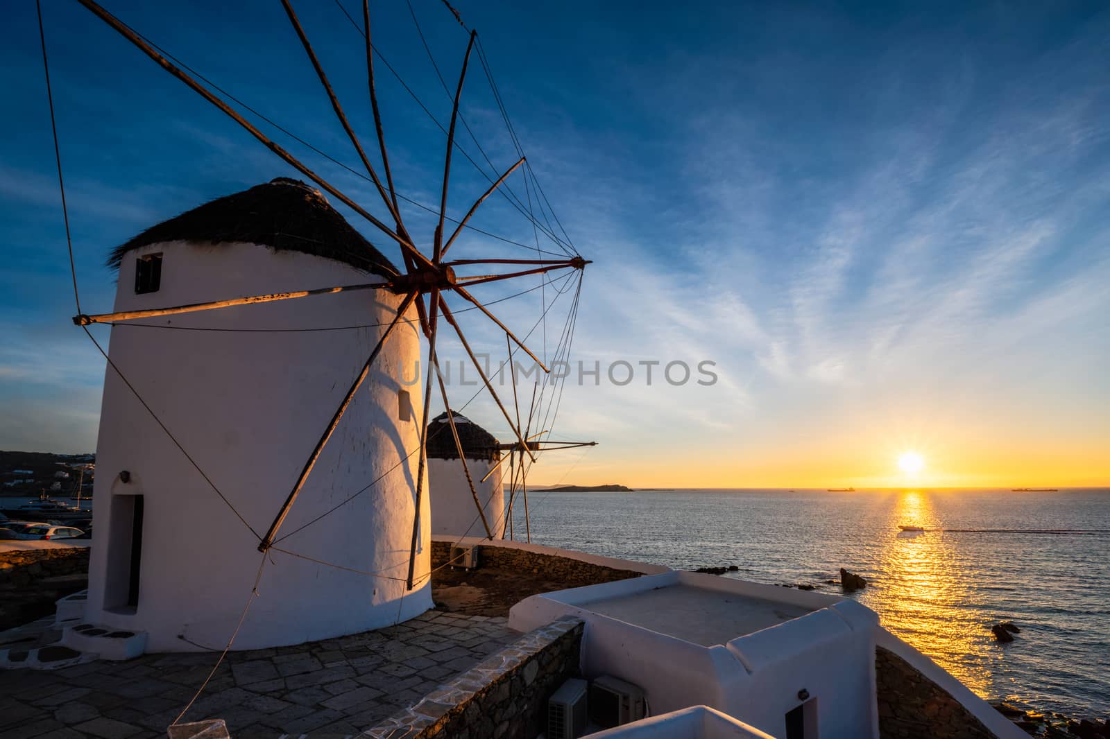 Scenic view of famous Mykonos town windmills. Traditional greek windmills on Mykonos island on sunset with dramatic sky, Cyclades, Greece. Walking with steadycam.
