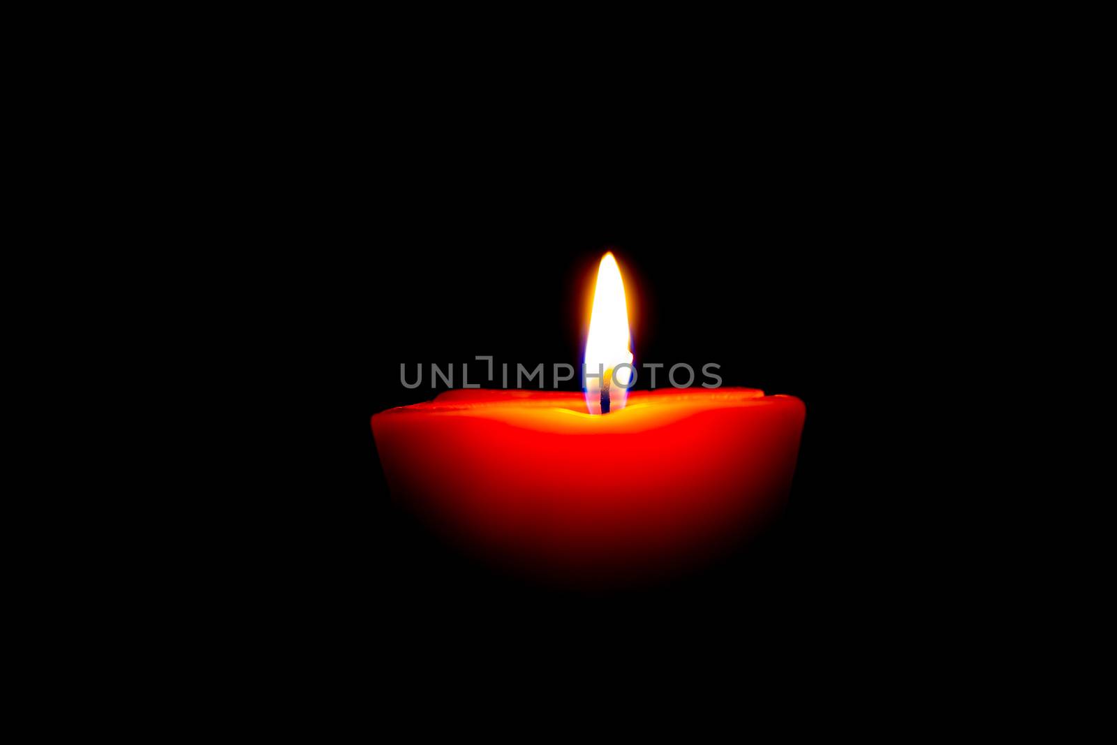 Closeup of burning candle isolated on black background.