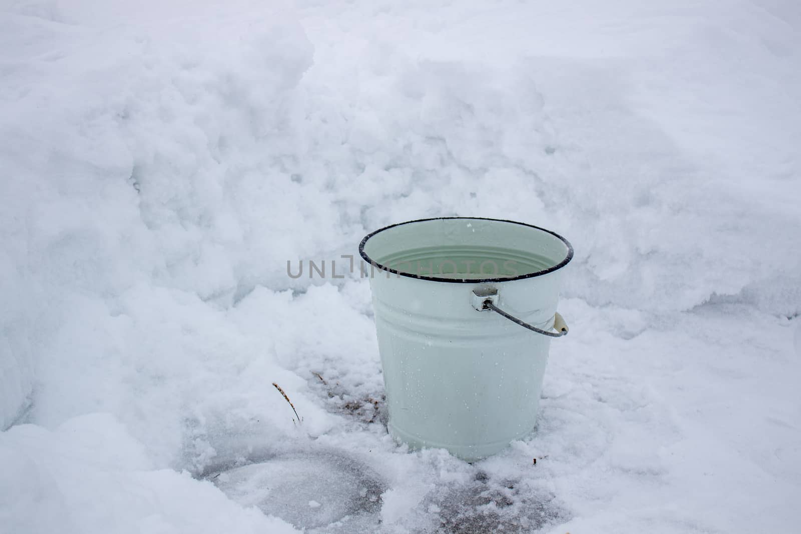 Bucket of water in the cold on the white snow