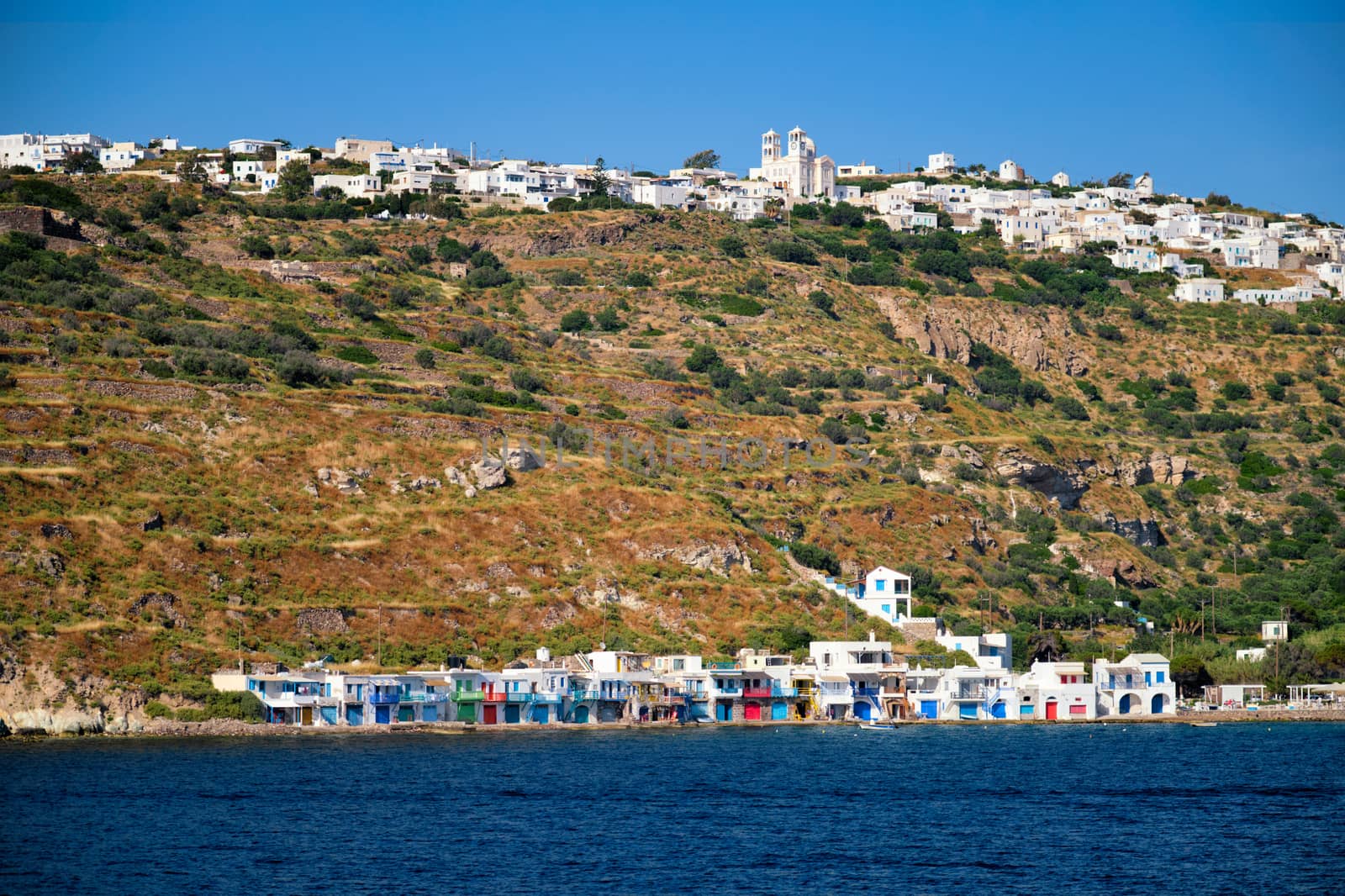 Klima and Plaka villages with whitewhashed traditional houses and orthodox church and windmills on Milos island, Greece