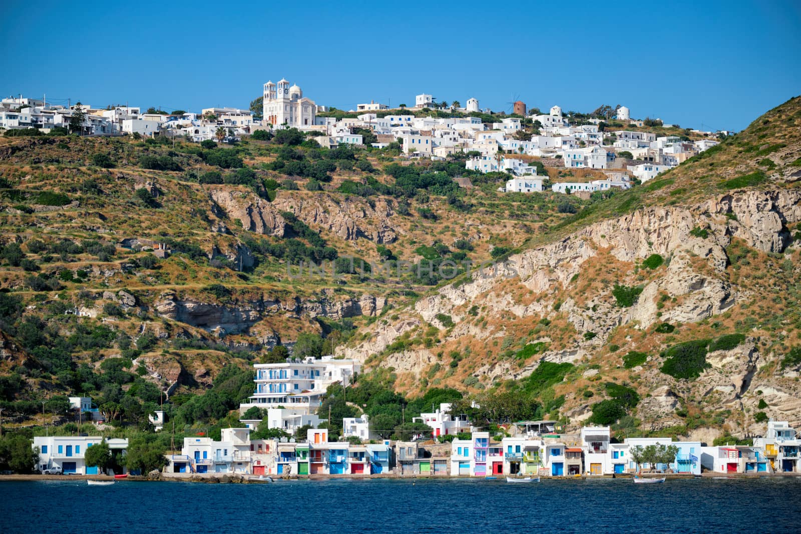 Klima and Plaka villages with whitewhashed traditional houses and orthodox church and windmills on Milos island, Greece