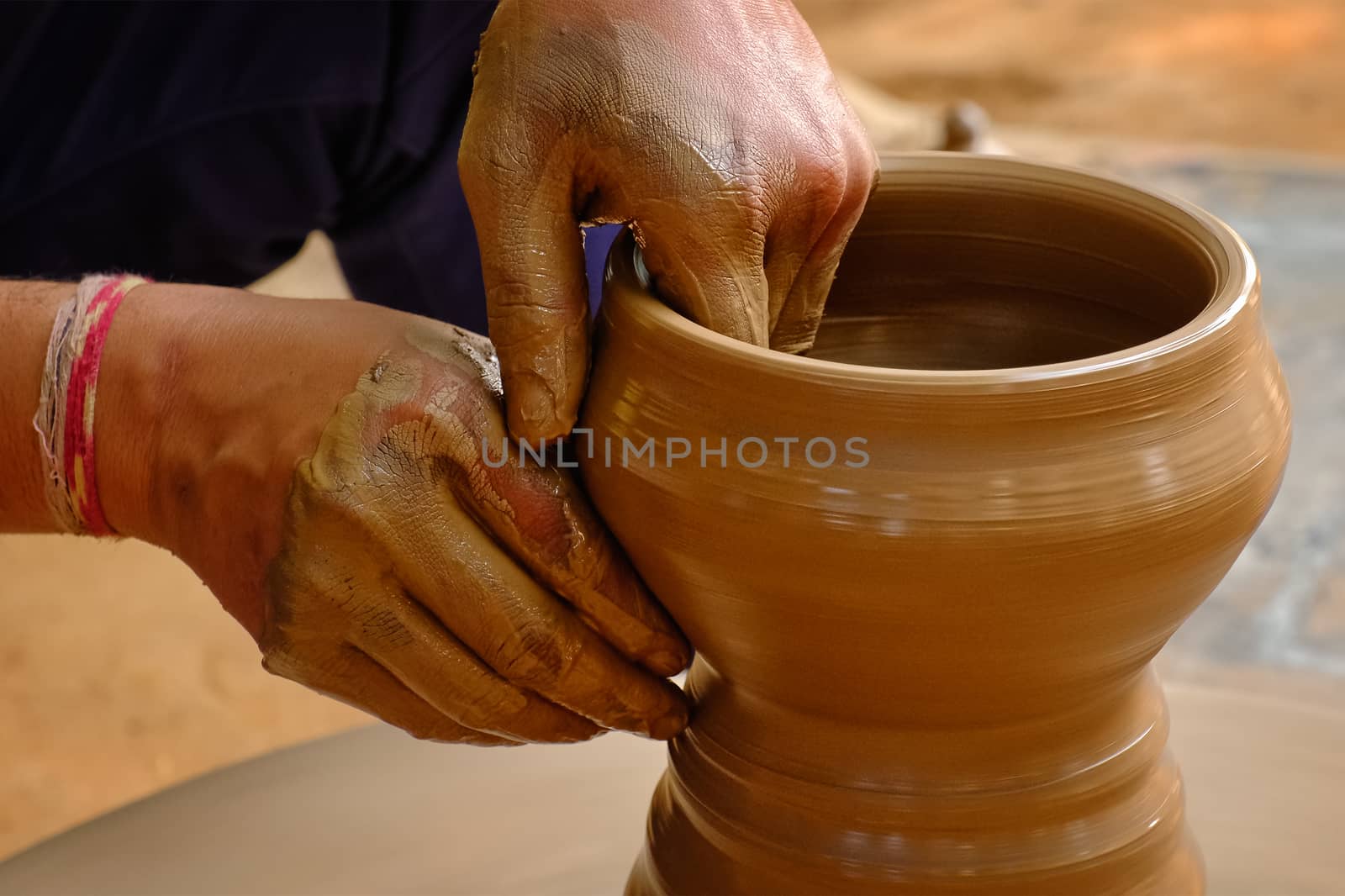 Pottery - skilled wet hands of potter shaping the clay on potter wheel by dimol