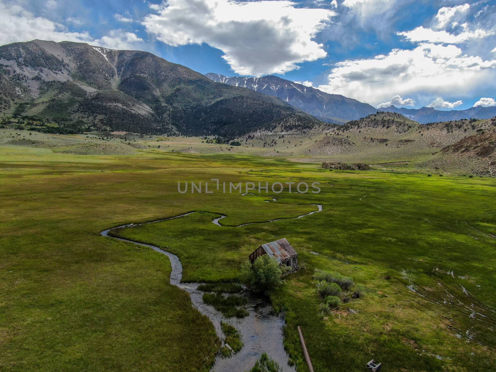 Aerial view of abandoned little wooden house barn next small river in the green valley, Aspen Spring by Bonandbon