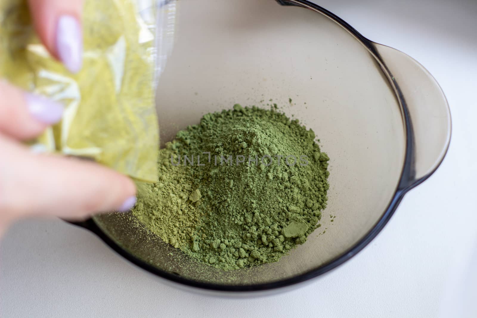 Mixing henna with a wooden spoon in a bowl for hair application of natural color like Indian henna mix