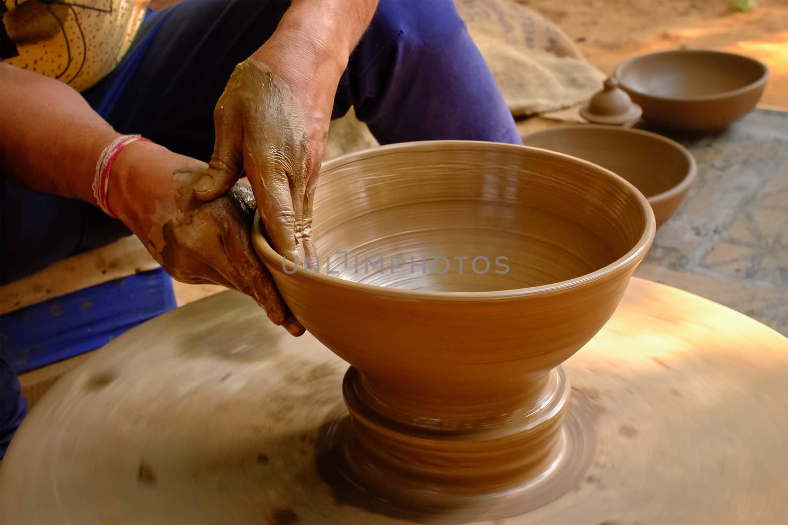 Pottery - skilled wet hands of potter shaping the clay on potter wheel by dimol