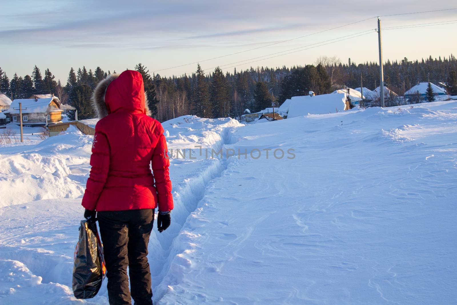 A girl in a red jacket walks through snowdrifts in Siberia, Russia
