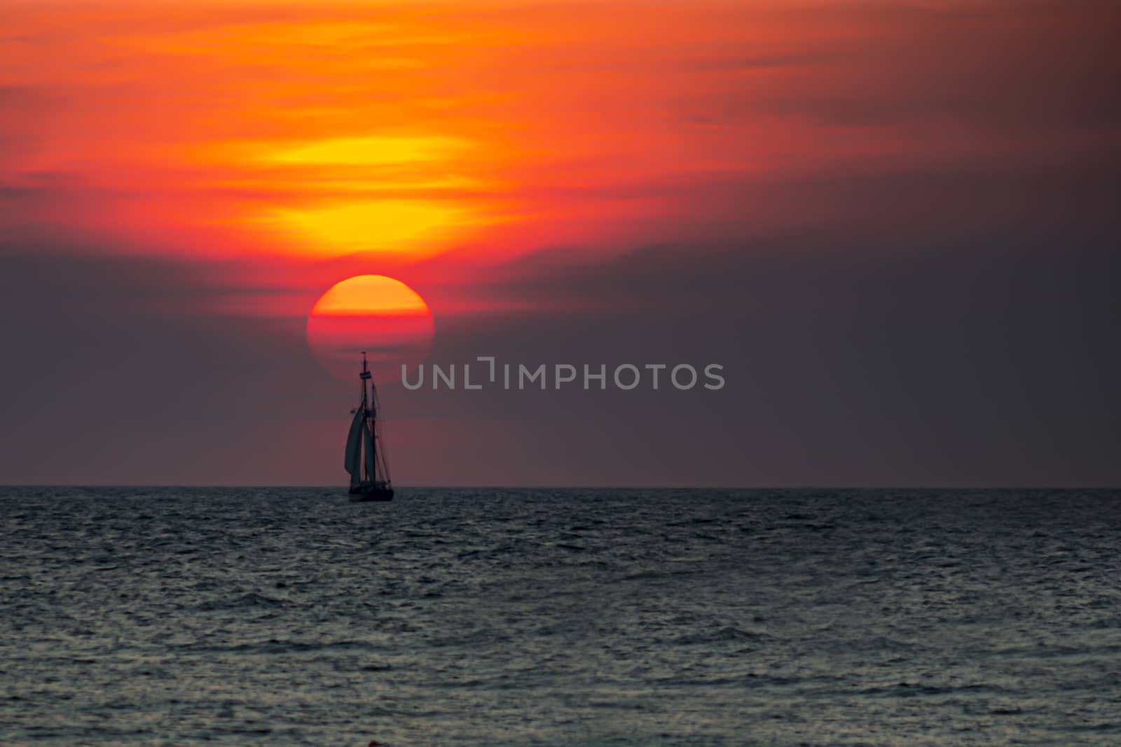 Tall ship, vessel, sailing and preparing the enter inside the harbor of Scheveningen at the vivid sunset moment, The Hague, Netherlands by ankorlight