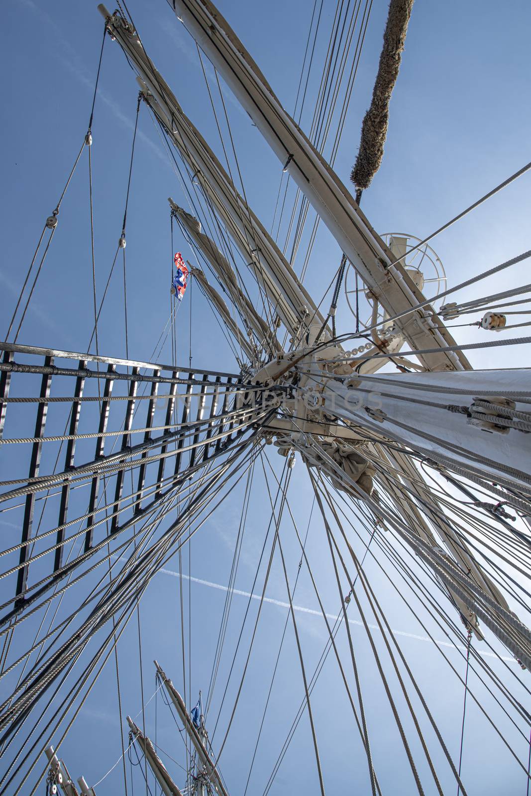 Up view of a high tall ship mast surrounded by ropes and lather 