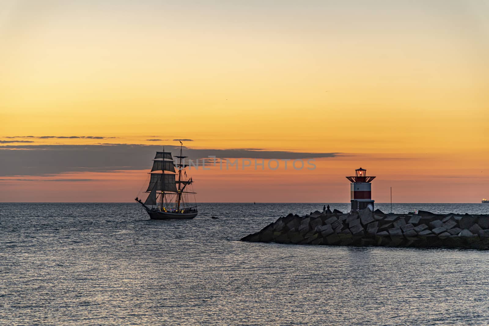 Tall ship, vessel, sailing and preparing the enter inside the harbor of Scheveningen at the vivid sunset moment, The Hague, Netherlands by ankorlight