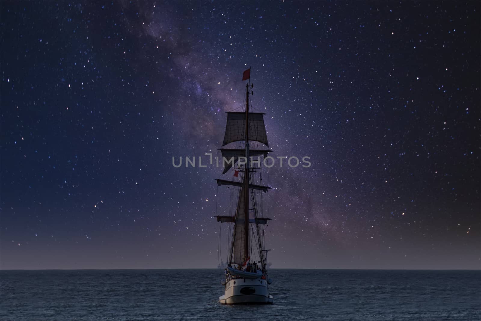 Antique tall ship, vessel leaving the harbor of The Hague, Scheveningen under a clear milky way sky