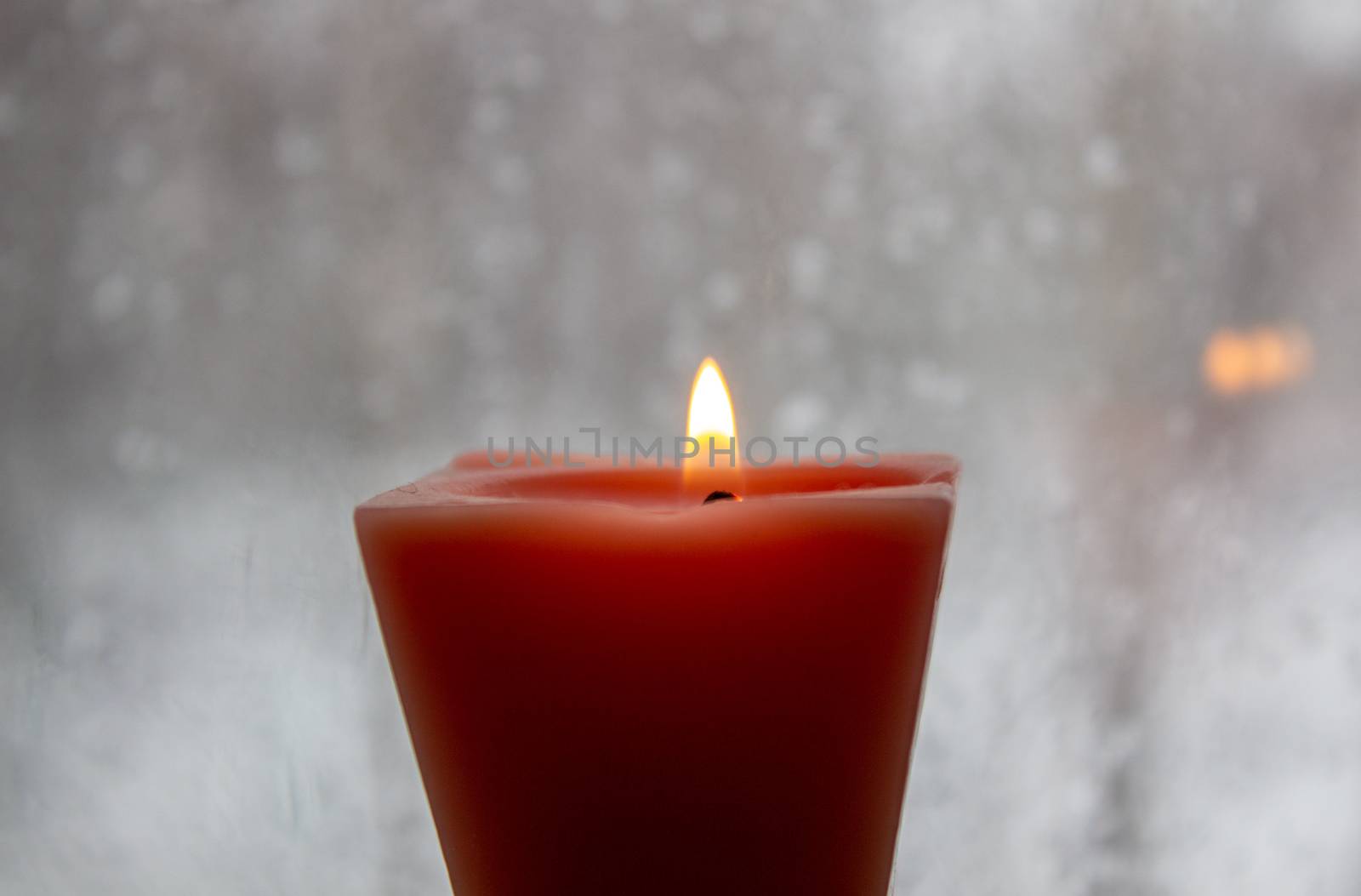 Candle burning near a frosted window in twilight. Winter evening. by AnatoliiFoto