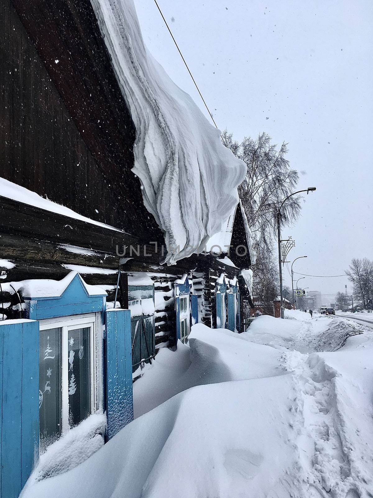 A lot of snow on the roof of the house and buildings. Winter in the country and in the city. The sun shines on the snow of the hemisphere curve, and the snow on the roof of the winter house is thick,