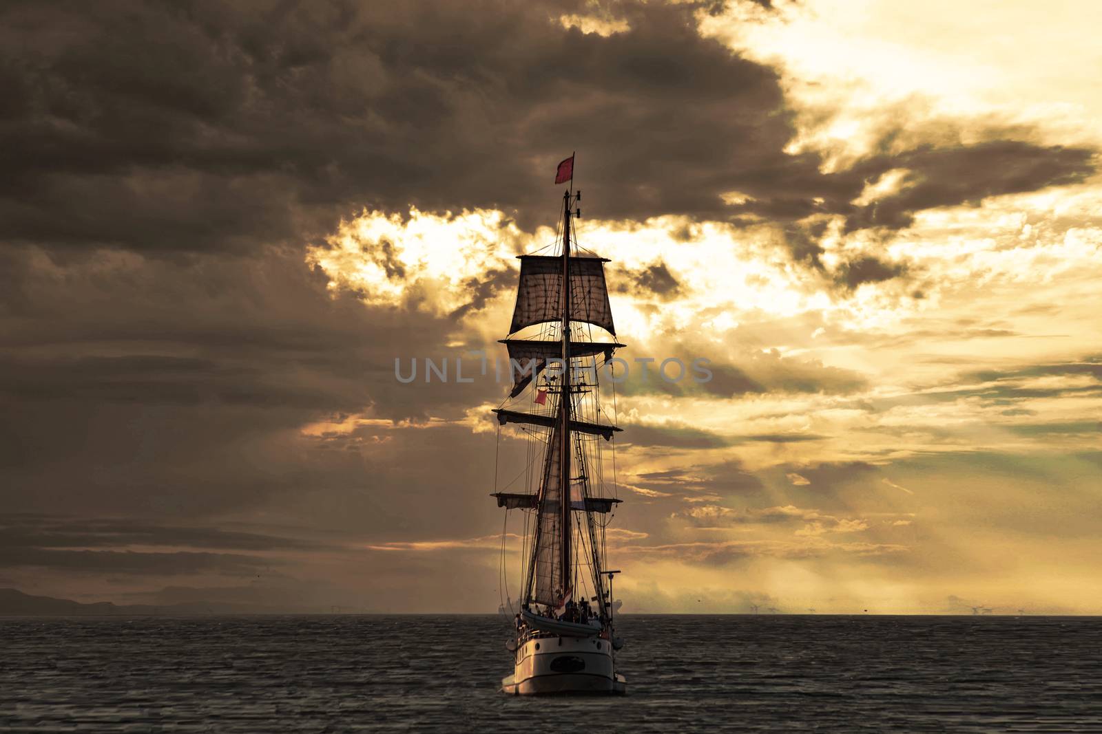 Antique tall ship, vessel leaving the harbor of The Hague, Scheveningen under a warm sunset and golden sky by ankorlight