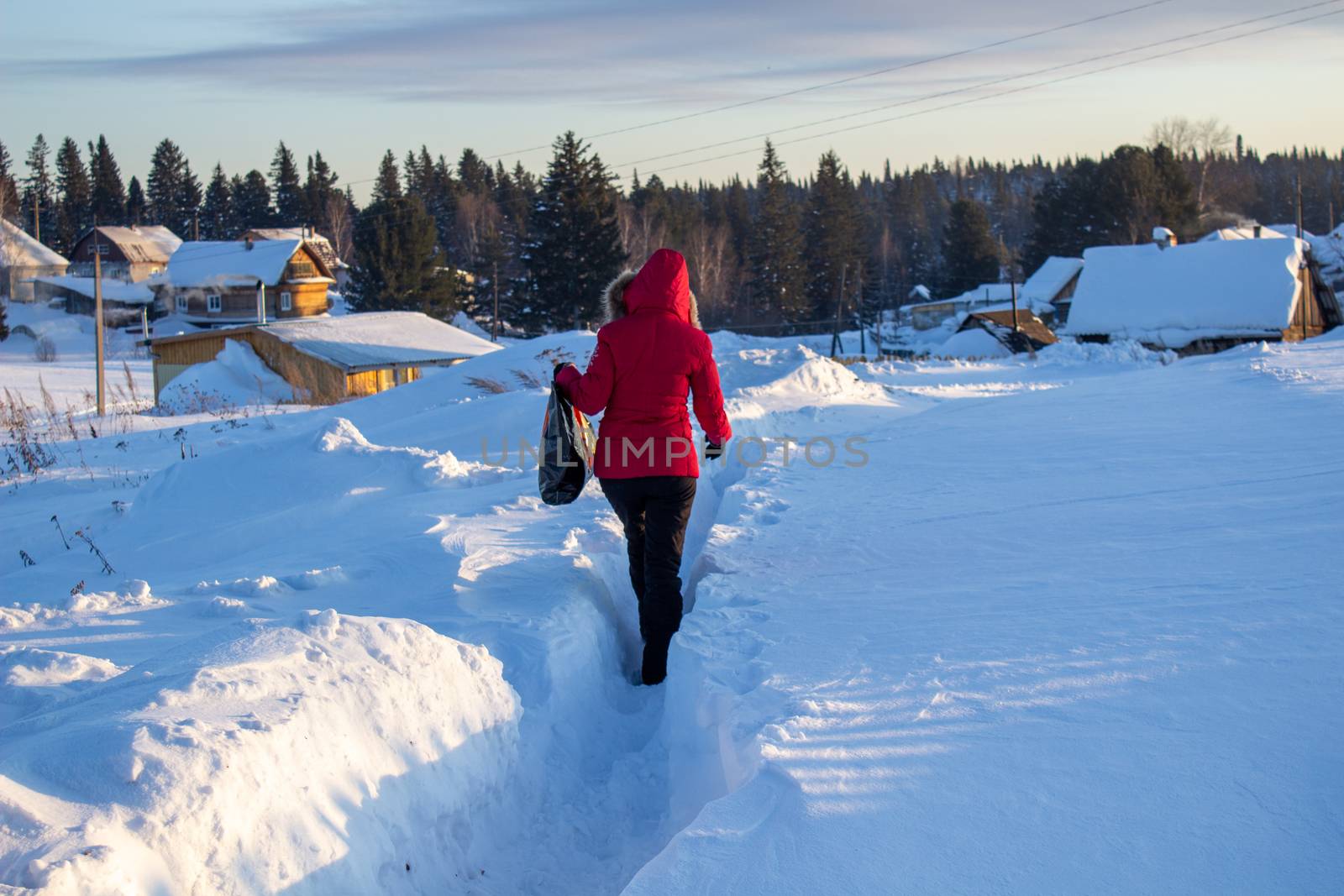 A girl in a red jacket walks through snowdrifts in Siberia, Russia