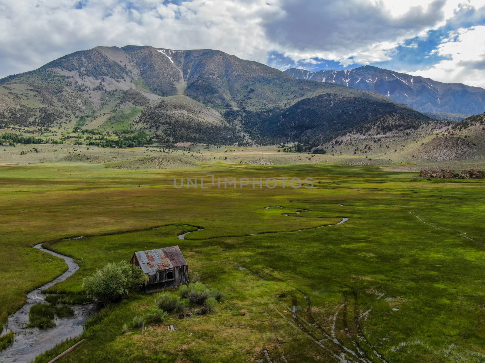 Aerial view of abandoned little small wooden house barn next small river in the green valley of a mountain, Aspen Spring, Mono County, California, USA. 