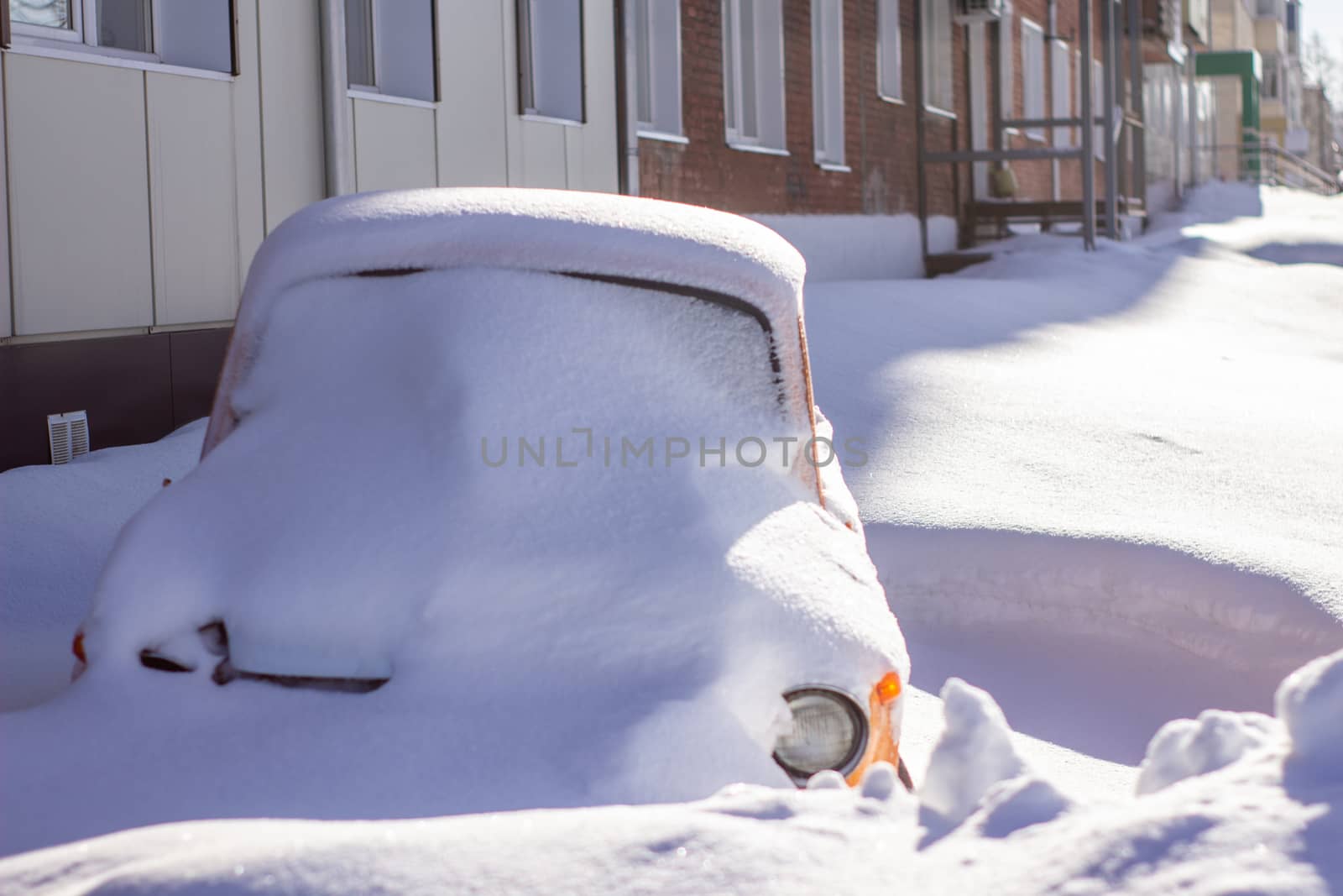 vehicles covered with snow in the winter blizzard in the parking lot.