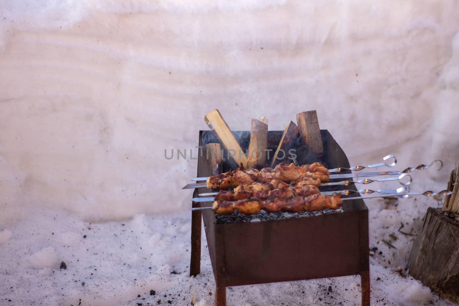 Cooking meat on the fire. Shish kebab on the grill. The grill is lit outside in winter. Fry shish kebabs on the grill