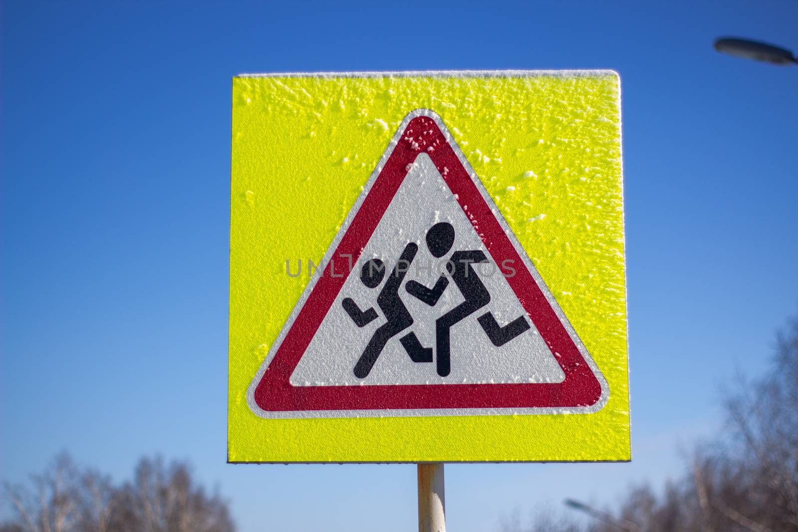 Pedestrian crossing sign on a yellow background. On a Sunny winter day