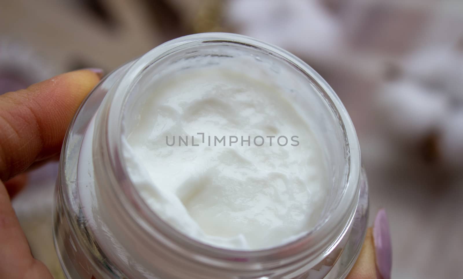 Closeup of young woman's hand holding jar of moisturizing cream in hands by AnatoliiFoto