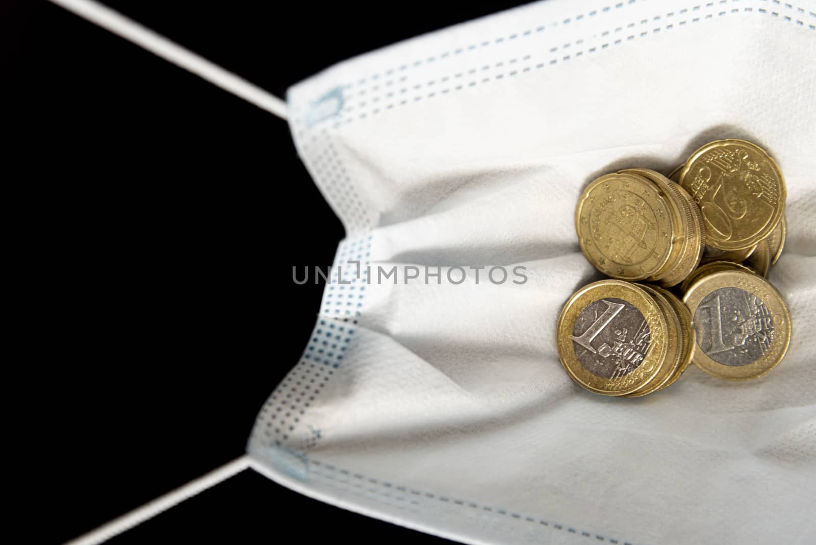Medical face mask with money, black background. World coronavirus economic losses concept. Concept of financial impact of covid-19 on European money area. Euros and coins.