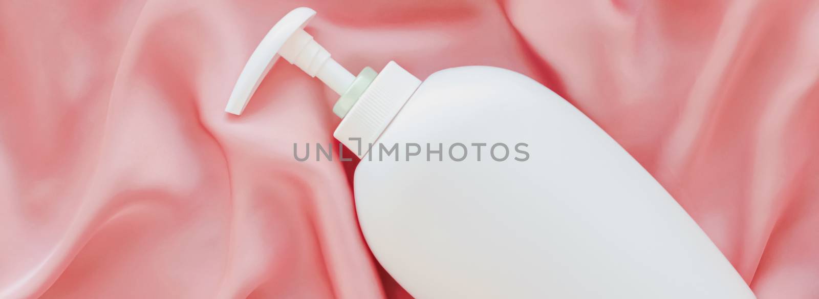 Blank label cosmetic container bottle as product mockup on pink silk background, hygiene and healthcare